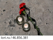 Горящие свечи и гвоздики с черной траурной лентой на грунтовом фоне. Стоковое фото, фотограф Pixel_shot / Фотобанк Лори