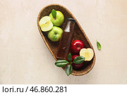 Корзина со стеклянной бутылкой свежего яблочного уксуса и фруктами на белом столе. Стоковое фото, фотограф Pixel_shot / Фотобанк Лори