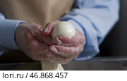 Close up for hands of a cheesemaker cutting mozzarella with hands, traditional food concept. Стоковое фото, фотограф David Kashakhi / Фотобанк Лори