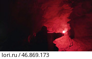 Young man exploring dark misty cave and leaving the entrance behind him. Стоковое фото, фотограф David Kashakhi / Фотобанк Лори