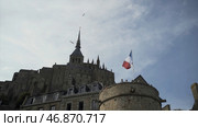 Bottom view of Mont Saint Michel castle in France on blue cloudy sky background with flying seaguls. Стоковое фото, фотограф David Kashakhi / Фотобанк Лори