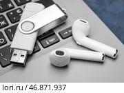 Белый USB-накопитель и беспроводные наушники на современном ноутбуке, крупным планом. Стоковое фото, фотограф Pixel_shot / Фотобанк Лори