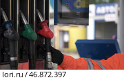 Close-up of a men's hand using a fuel nozzle at a gas station. Стоковое фото, фотограф David Kashakhi / Фотобанк Лори