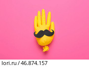 Надутая резиновая перчатка с бумажными усами на розовом фоне. Стоковое фото, фотограф Pixel_shot / Фотобанк Лори