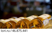 Blurred bottles of white and rose wine are nicely laid out in a row on a shelf in a large supermarket. Стоковое фото, фотограф David Kashakhi / Фотобанк Лори