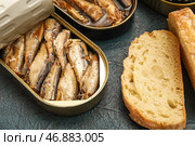 Открытые жестяные банки со шпротами в масле и хлебом на черном столе. Стоковое фото, фотограф Pixel_shot / Фотобанк Лори