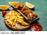 Тарелка вкусной жареной трески с картофелем фри на зеленом фоне. Стоковое фото, фотограф Pixel_shot / Фотобанк Лори