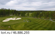 Golfers hitting golf shot with club on course while on summer vacation, aerial. Стоковое фото, фотограф David Kashakhi / Фотобанк Лори