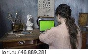 Over the shoulder shot of a woman typing on a computer laptop with a chromakey green screen. Стоковое фото, фотограф David Kashakhi / Фотобанк Лори