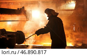 Steel worker removing slag from the electric induction crucible melting furnace at the metallurgical plant, hard work conceprt. Стоковое фото, фотограф David Kashakhi / Фотобанк Лори