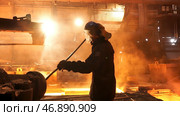 Side view of the perator remove waste from furnace pipe at the iron melting plant. Стоковое фото, фотограф David Kashakhi / Фотобанк Лори