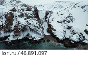Aerial of steep rocks covered by white snow by the blue sea, beauty of winter nature concept. Стоковое фото, фотограф David Kashakhi / Фотобанк Лори