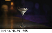 Thick alcoholic beverage is being poured into transparent glass on dark background. Стоковое фото, фотограф David Kashakhi / Фотобанк Лори