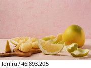 Вкусный фрукт памело, кожура и деревянная доска с кусочками на розовом грунтовом фоне. Стоковое фото, фотограф Pixel_shot / Фотобанк Лори