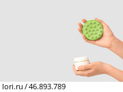Женские руки с силиконовой головкой массажной щетки и банкой косметического продукта на белом фоне. Стоковое фото, фотограф Pixel_shot / Фотобанк Лори