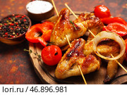 Деревянная доска с жареными куриными крылышками и овощами на гранж-фоне. Стоковое фото, фотограф Pixel_shot / Фотобанк Лори