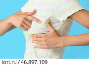 Молодая женщина чувствует дискомфорт в груди на цветном фоне. Концепция осведомленности о раке. Стоковое фото, фотограф Pixel_shot / Фотобанк Лори
