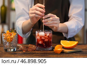 Бармен готовит вкусный коктейль Negroni за столиком в баре. Стоковое фото, фотограф Pixel_shot / Фотобанк Лори