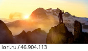 Hiker on rock summit during sunrise enjoying majestic mountain view, symbolizing success motivation determination adventure independence challenge inspiration, ambition self-growth exploration. Стоковое фото, фотограф Павел Муравьев / Фотобанк Лори