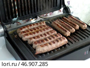 Приготовление чевапчичи (колбасок) на электрическом гриле - Cooking chevapchichi (sausage) on an electric grill. Стоковое фото, фотограф Владислав Дельдюгинов / Фотобанк Лори