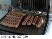 Приготовление чевапчичи (колбасок) на электрическом гриле - Cooking chevapchichi (sausage) on an electric grill. Стоковое фото, фотограф Владислав Дельдюгинов / Фотобанк Лори