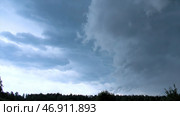Storm or rain clouds hanging above green forest and meadow. Стоковое фото, фотограф David Kashakhi / Фотобанк Лори