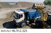 The bulldozer works at the quarry , loading excavator with sand. Стоковое фото, фотограф David Kashakhi / Фотобанк Лори