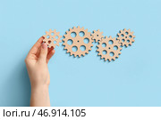 Рука с деревянными шестернями на светло-голубом фоне. Стоковое фото, фотограф Pixel_shot / Фотобанк Лори