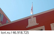 The government building made in red on top with a decorated flag that moves because of the wind. Стоковое фото, фотограф David Kashakhi / Фотобанк Лори