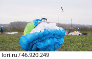 Man in overalls drags parachute to gathering place in field. Стоковое фото, фотограф David Kashakhi / Фотобанк Лори