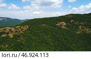 Amazing endless landscape of the high mountain ranges covered by green trees and shrubs against the blue cloudy sky in summer day. Стоковое фото, фотограф David Kashakhi / Фотобанк Лори