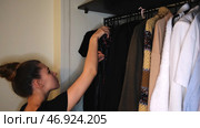 Close-up of the beautiful young woman hanging her clothes in the wardrobe at home. Стоковое фото, фотограф David Kashakhi / Фотобанк Лори