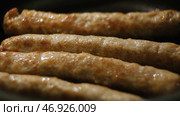 Close-up of thin long pork sausages in natural casing fried on the pan. Стоковое фото, фотограф David Kashakhi / Фотобанк Лори