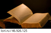 Ancient book with old yellow pages and patterns flipping over dark background. Стоковое фото, фотограф David Kashakhi / Фотобанк Лори