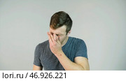 Young man sneezing on a white background, slow motion. Стоковое фото, фотограф David Kashakhi / Фотобанк Лори