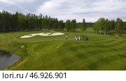 Golfers hitting golf shot with club on course while on summer vacation, aerial. Стоковое фото, фотограф David Kashakhi / Фотобанк Лори