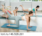 Girl leads class women, standing on all fours, performing exercises with wide elastic skip rope. Стоковое фото, фотограф Яков Филимонов / Фотобанк Лори