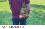 A man walking and carrying brown mesh string knitted shopping bag with groceries. Eco friendly, reusable shopping bag. Zero waste and plastic free concept. Стоковое видео, видеограф Ирина Старикова / Фотобанк Лори