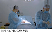 Two male surgeons in a special uniform performing medical procedure. Стоковое фото, фотограф David Kashakhi / Фотобанк Лори