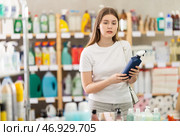Girl looking for trademark sign on label, chooses eco friendly tile cleaner spray. Стоковое фото, фотограф Яков Филимонов / Фотобанк Лори