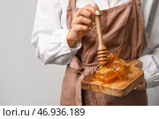 Женщина с деревянной доской из сот и ковша на светлом фоне. Стоковое фото, фотограф Pixel_shot / Фотобанк Лори