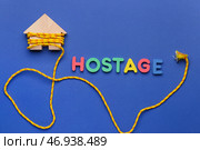 Деревянный дом с обвязанной веревкой и надписью HOSTAGE на цветном фоне. Стоковое фото, фотограф Pixel_shot / Фотобанк Лори