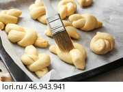 Смазывать сырые чесночные булочки маслом на противне, крупным планом. Стоковое фото, фотограф Pixel_shot / Фотобанк Лори
