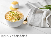 Чаша с вкусным кус-кусом и зеленым луком на светлом деревянном фоне. Стоковое фото, фотограф Pixel_shot / Фотобанк Лори