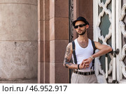 Stylish Individual Leans Against an Ornate Wall Showcasing a Confident Attitude in Urban Setting. Стоковое фото, фотограф Aleksandr Golubev / Фотобанк Лори