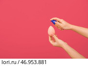 Женщина наносит тональный крем на губку для макияжа на цветном фоне. Стоковое фото, фотограф Pixel_shot / Фотобанк Лори