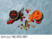 Бутылки эфирного масла, баночки со скрабом и ягодами шиповника на цветном фоне. Стоковое фото, фотограф Pixel_shot / Фотобанк Лори