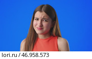 Girl with a confused expression on a bright blue background during a discussion or interview. Стоковое видео, видеограф Сергей Толмачёв / Фотобанк Лори
