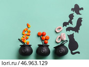 Ведьмины котлы с конфетами и хэллоуинским декором на синем фоне. Стоковое фото, фотограф Pixel_shot / Фотобанк Лори