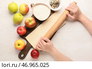 Женщина раскатывает тесто для яблочного штруделя на белом фоне. Стоковое фото, фотограф Pixel_shot / Фотобанк Лори